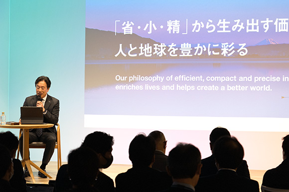 ステージ上で講演を行っている毛籠勝弘氏