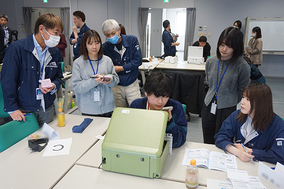 プリンターに触れながら作業している人と観察する人たち